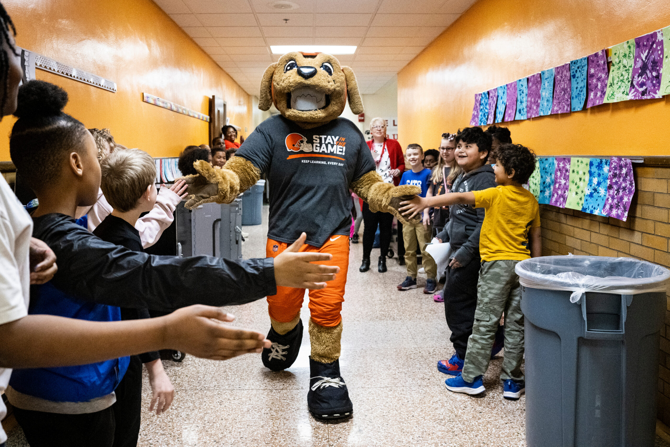 Cleveland Brown mascot walking down a hallway lined with kids