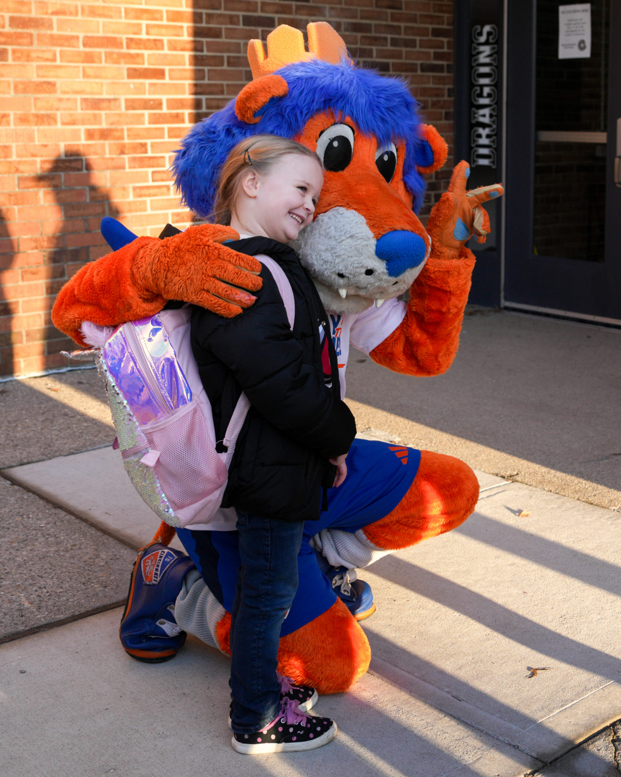 A mascot poses with a young girl