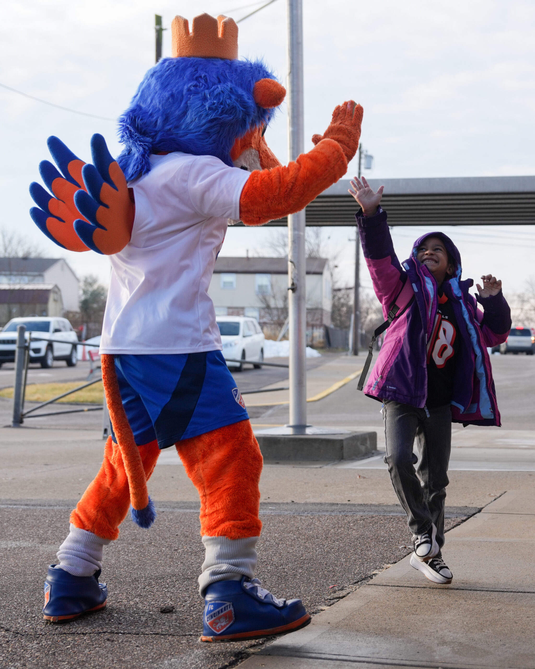 A mascot high fives a young boy