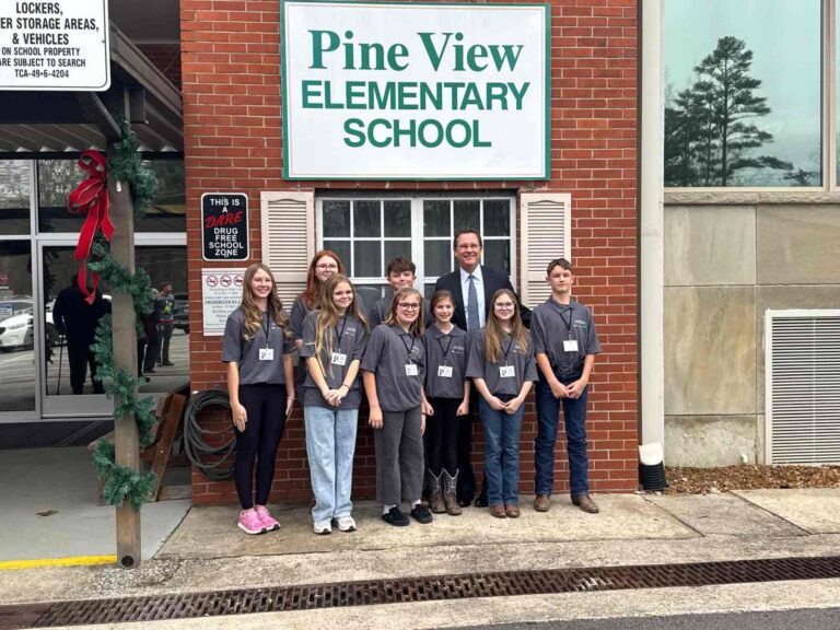 A teacher and students standing in front of Pine View Elementary School
