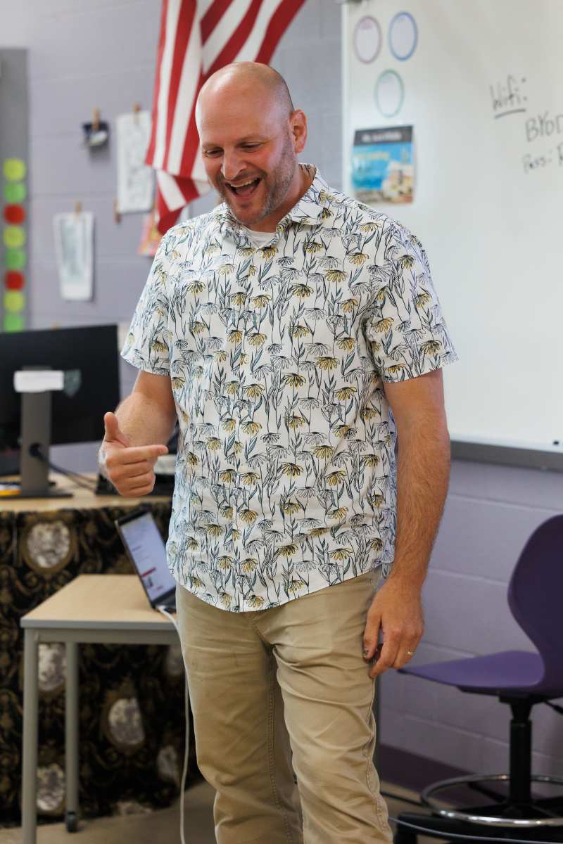 Man speaking in a classroom in front of a whiteboard