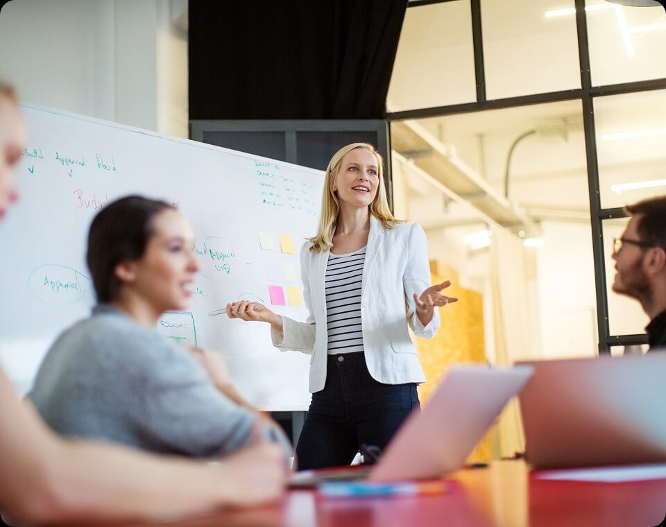 A woman standing and speaking to others seated in a room