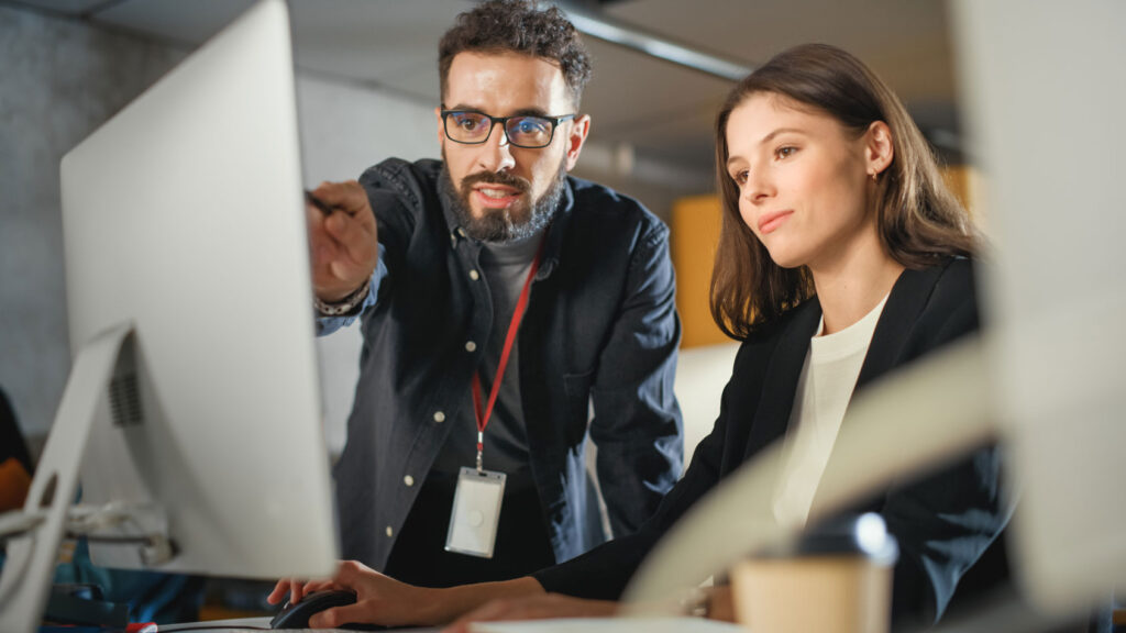 A man and woman pointing and looking at a monitor